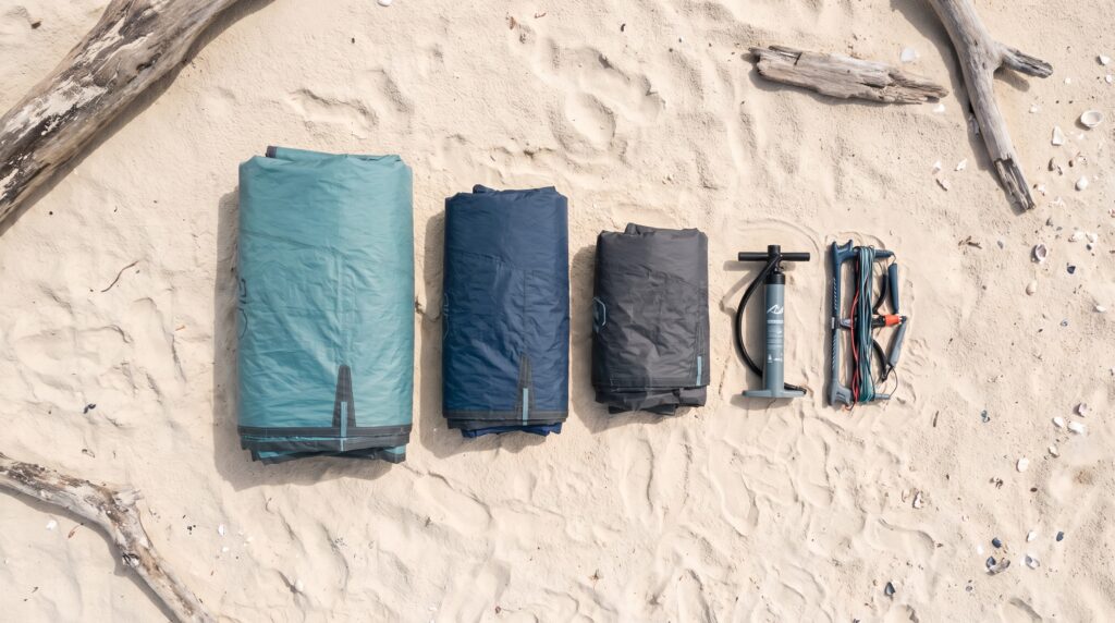 Três kites de kitesurf de tamanhos diferentes na praia