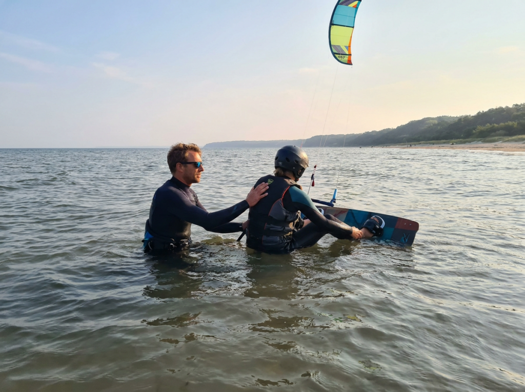 Instructor de kite ayuda en el arranque en el agua dentro del agua